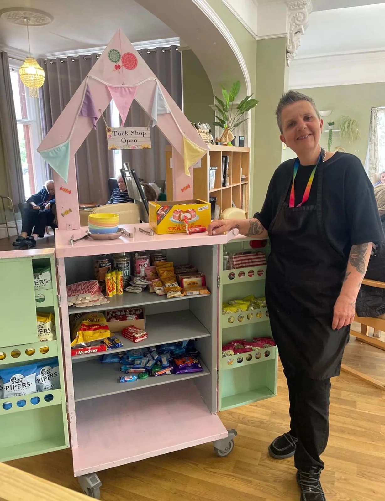 A team member standing beside a colourful snack trolley at Braydeston Court.