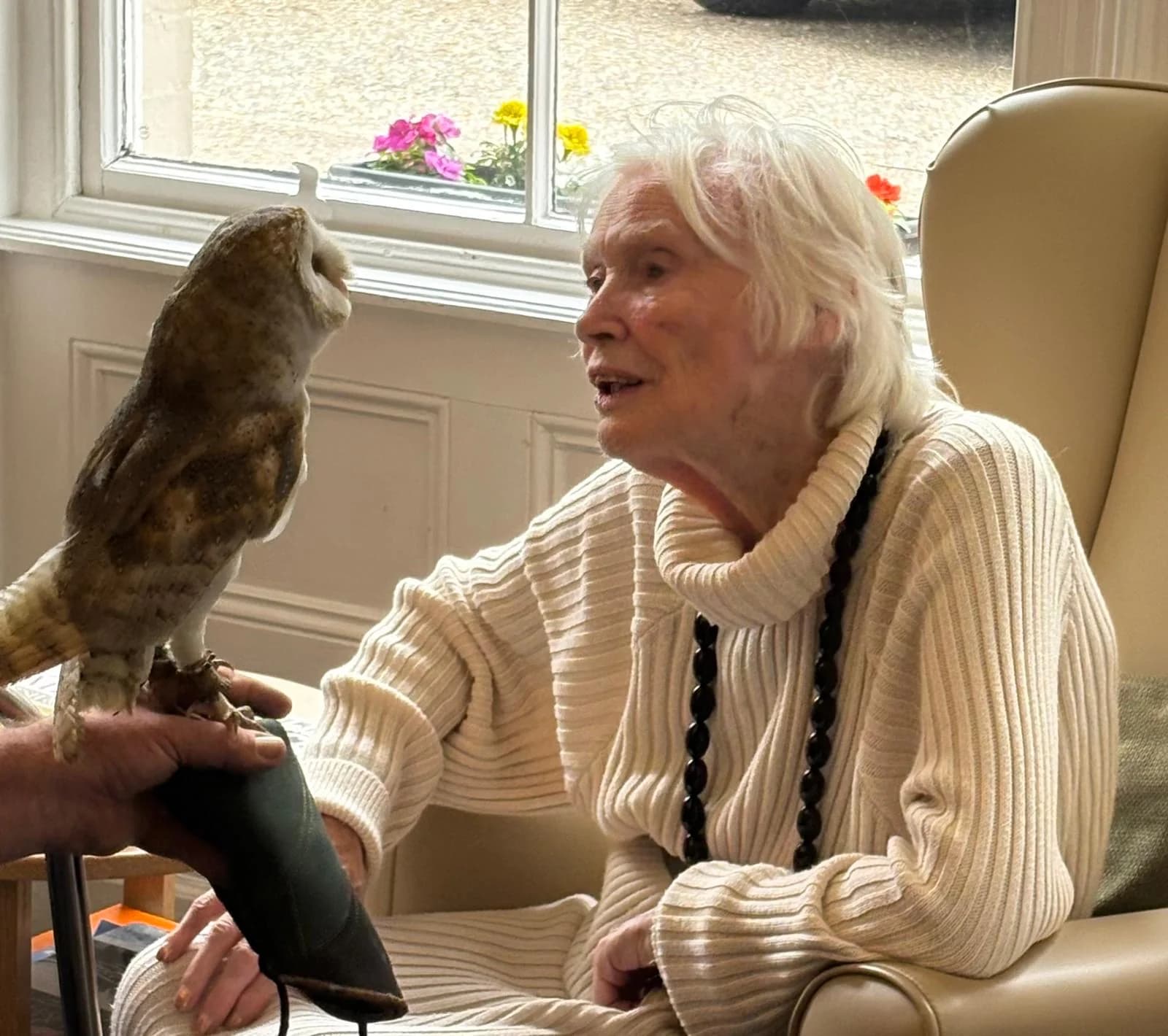 A resident smiling while meeting a visiting owl at Martham Lodge.