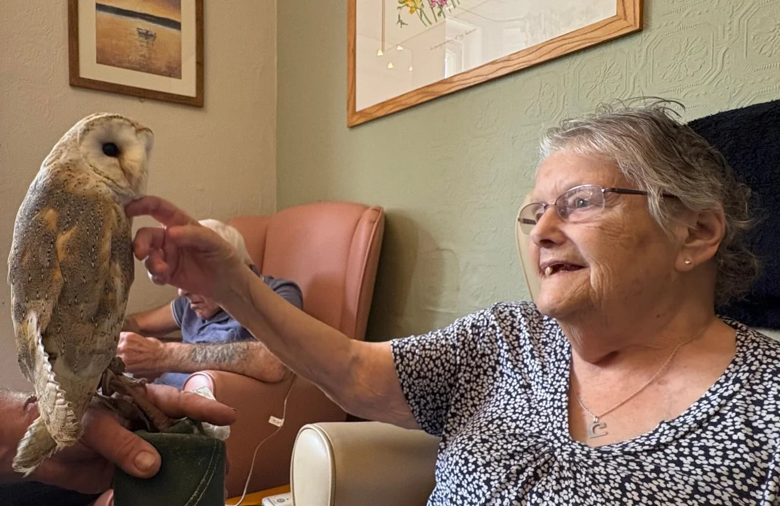 A resident reaching out towards a visiting owl during an animal visit at Martham Lodge.